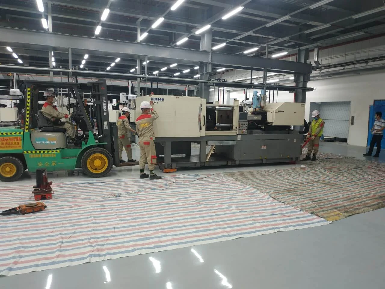 Hình ảnh xe nâng Thành Nguyên sử dụng kích rùa và kích thủy lực để hỗ trợ di chuyển lắp đặt máy móc trong nhà xưởng
