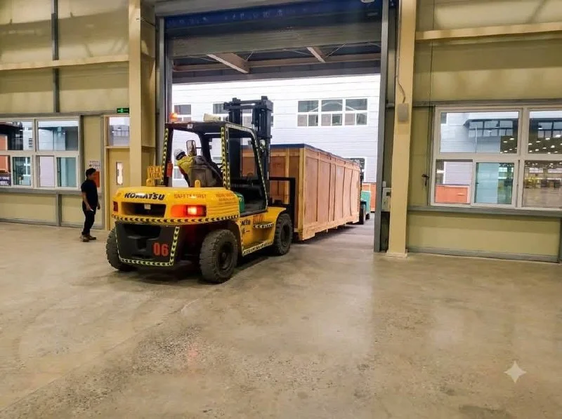 Xe nâng Komatsu Thành Nguyên đang di chuyển kiện máy công nghiệp dài qua cửa xưởng